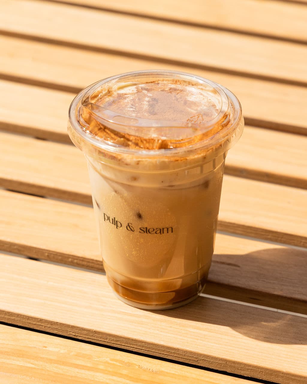 An iced latte catching the morning sunshine on our outdoor bench