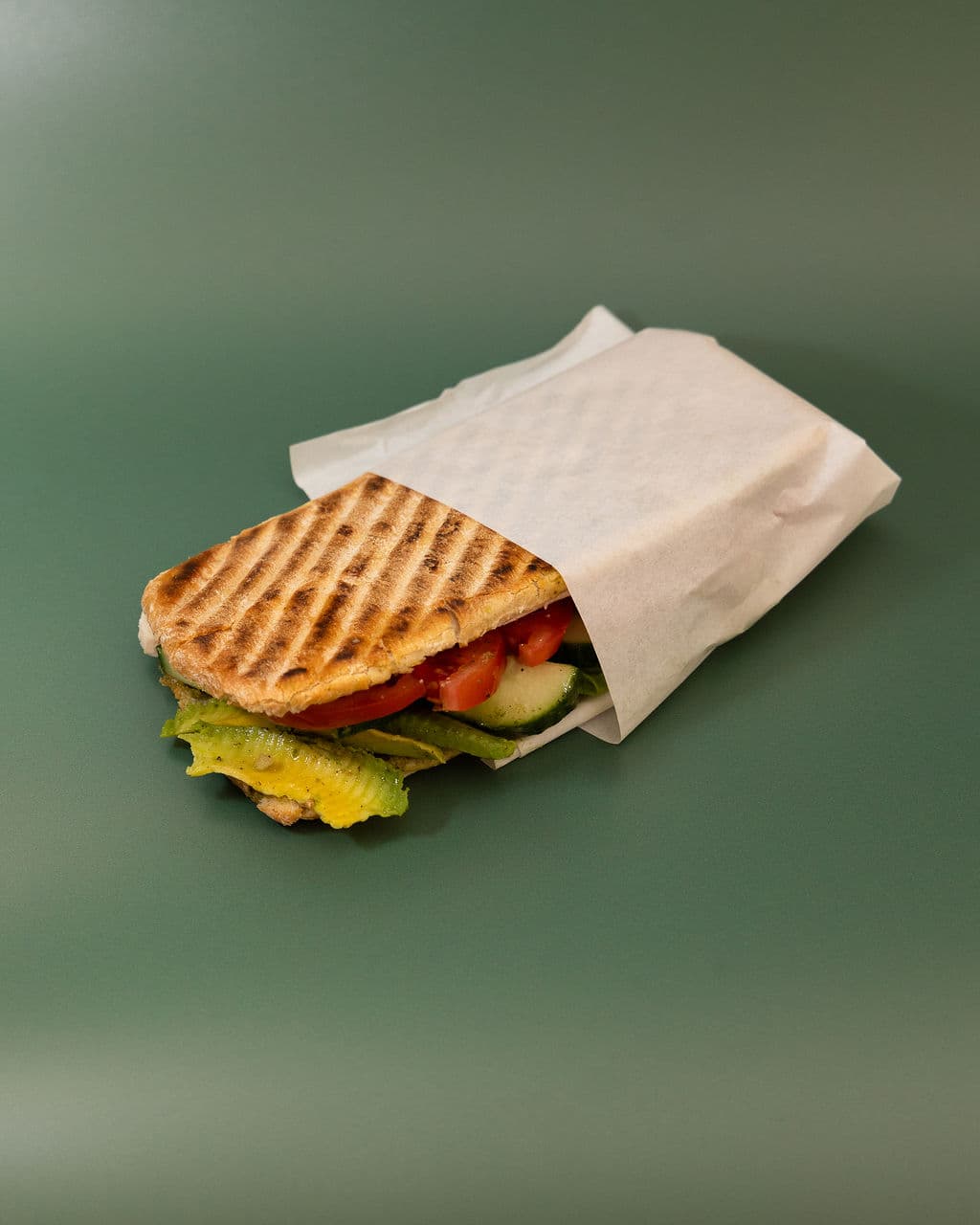 A freshly toasted sandwich filled with avocado, tomato and cucumber